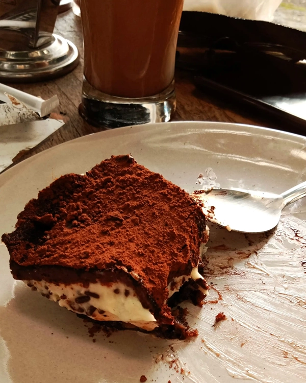 Tiramisu upplagd på en tallrik med en sked bredvid.